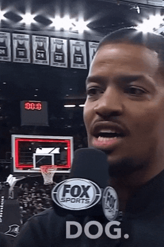 a man wearing a fox sports microphone is talking into it