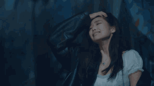 a woman in a white shirt and black jacket is crying