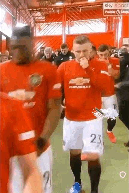 a man wearing a red shirt with the number 23 on it walks with another man