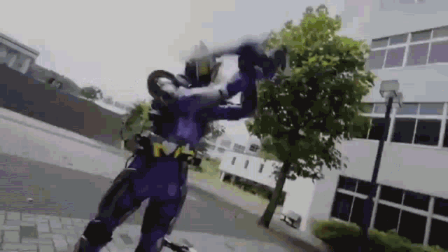 a man in a purple superhero costume is fighting another man with a sword .