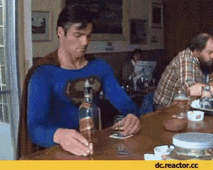 a man in a superman costume sits at a table