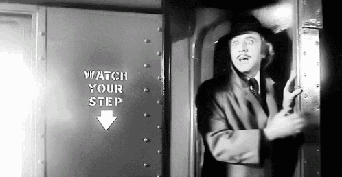 a man in a suit is standing in front of a sign that says " watch your step "
