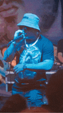 a man singing into a microphone while wearing a blue shirt with a picture of a horse on it