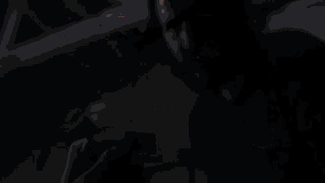 a man in a black coat is standing in a dark room with a window