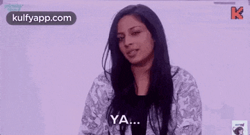 a woman with long black hair is standing in front of a white board and saying ya .