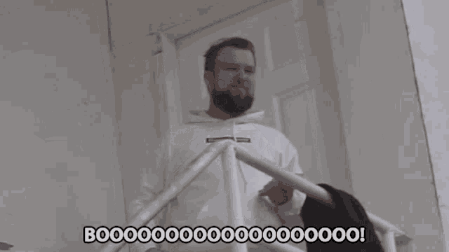 a man with a beard is standing on a set of stairs and says booo