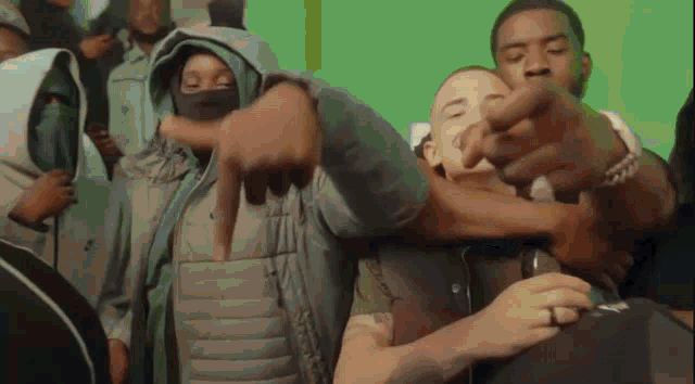 a group of people are standing in a room with a green screen in the background .