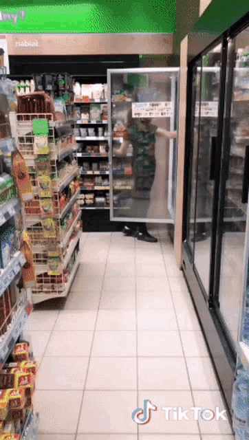 a person standing in a grocery store next to a refrigerator that says tiktok on it