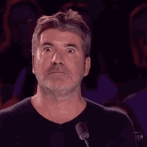 a man with a beard is standing in front of a microphone making a funny face