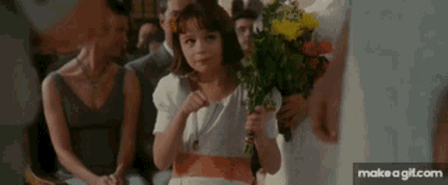 a little girl is holding a bouquet of flowers while sitting in a church .