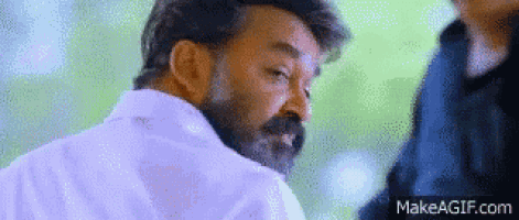 a man with a beard and mustache is wearing a white shirt and looking at the camera .