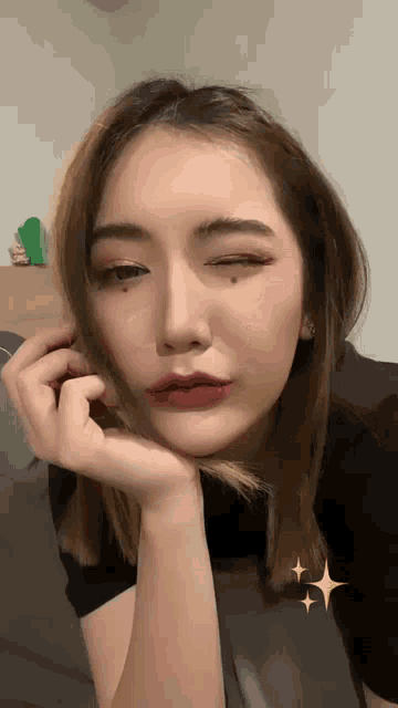 a close up of a woman 's face with her hand on her face