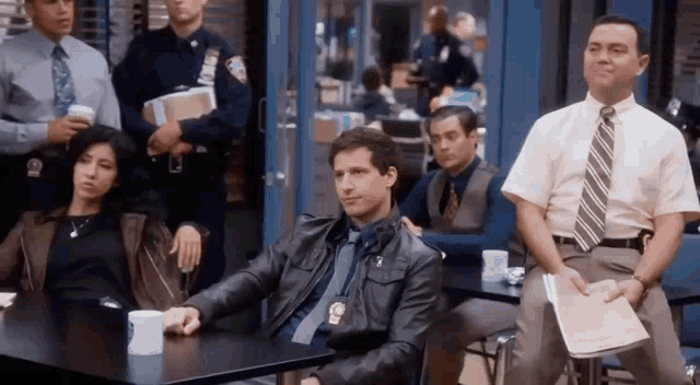 a group of police officers are sitting at a table .