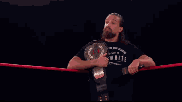 a man in a black shirt that says white is holding a wrestling belt