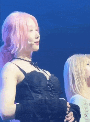 a woman with pink hair is standing next to another woman