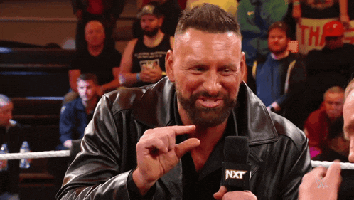 a man with a beard is talking into a microphone that says nxt on it