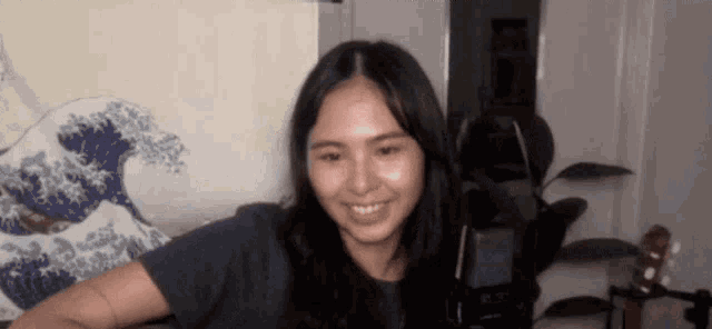 a woman is sitting on a couch smiling in front of a microphone .