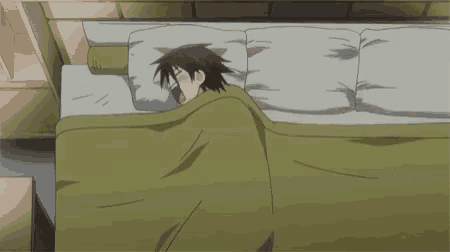 a man is sleeping in a bed with a green blanket and a pillow .