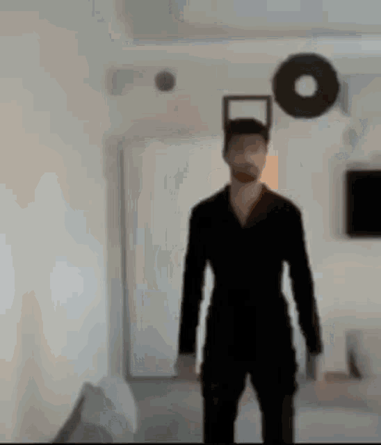 a man in a black suit is standing in a room with a circle on the wall .