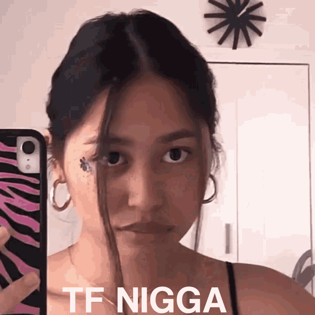 a woman taking a picture of herself with the words tf nigga above her