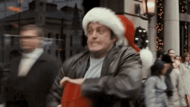 a man wearing a santa hat is holding a red bag .