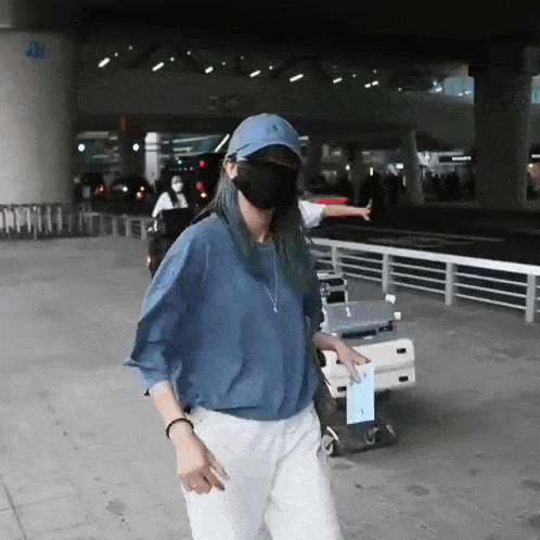 a woman wearing a blue shirt and white pants is wearing a mask