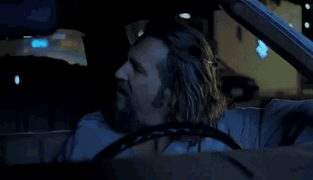 a man wearing sunglasses is driving a car with a flower on the windshield