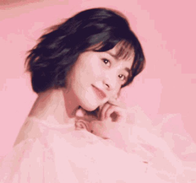 a woman in a pink dress is looking at the camera with a pink background