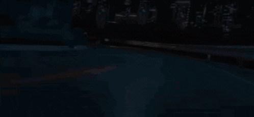 a car is driving down a highway at night with a city in the background