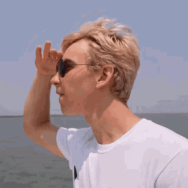 a young man wearing sunglasses looks out over the ocean