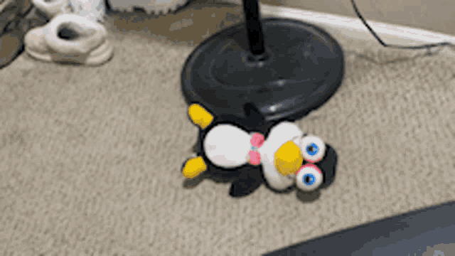 a stuffed penguin is laying on its back on the floor