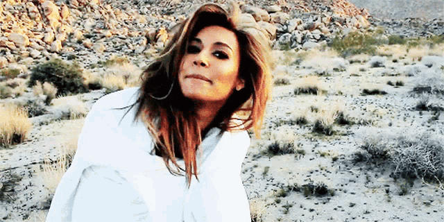a woman wearing a white shirt is standing in the desert