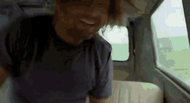 a man in a blue shirt is smiling in a car