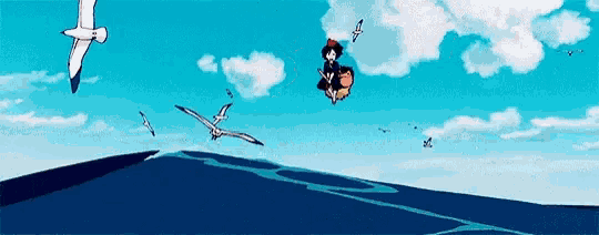 a group of seagulls are flying over a body of water with a person flying in the air .