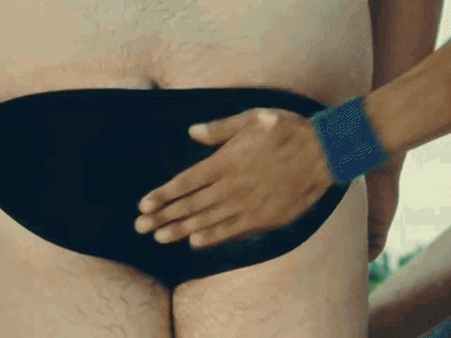 a man in a black bathing suit is being touched by another man .