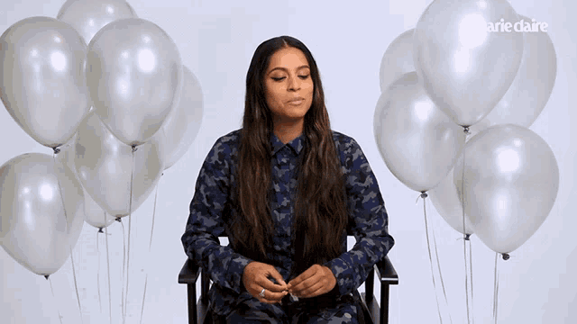 a woman is sitting in front of a bunch of white balloons with the word marie claire on the bottom