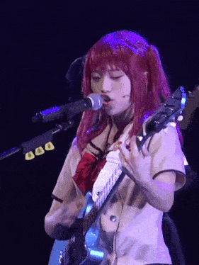 a girl singing into a microphone while playing a guitar