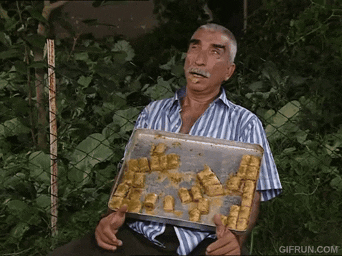 a man with a mustache is holding a tray of food with gifrun.com written on the bottom