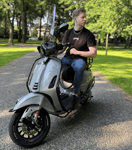 a man is sitting on a scooter with a black tire