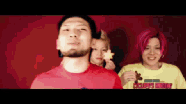 a man and two women are standing next to each other in front of a red wall .