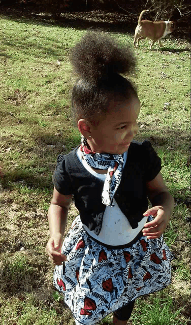a little girl wearing a dress that says ' spiderman ' on it is standing in the grass