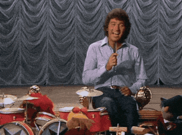 a man is singing into a microphone while playing drums