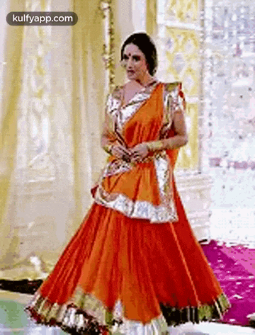 a woman in a red and gold dress is dancing .