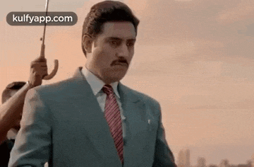 a man in a suit and tie is holding a umbrella .