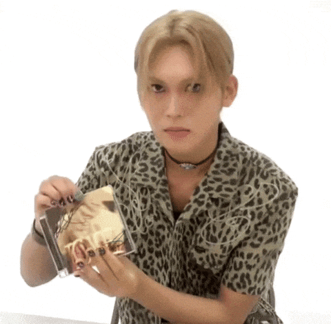a young man wearing a leopard print shirt is holding a cd .