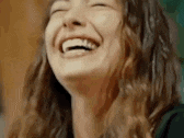 a close up of a woman laughing with her eyes closed and her mouth open .