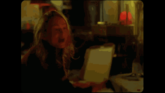 a woman is screaming with her hands on her head in a dark room