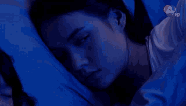 a woman is laying in bed with a blue blanket and the number 7 on the corner