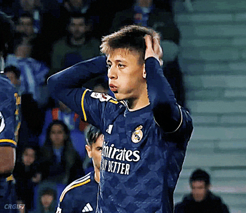 a soccer player wearing a blue emirates fly better jersey holds his head