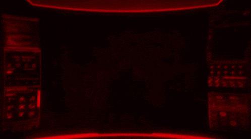 a red light is shining on a black background with a brick wall in the background